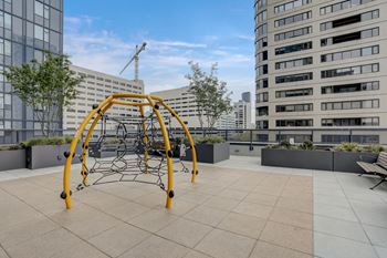 A playground with a yellow swing set on a rooftop.